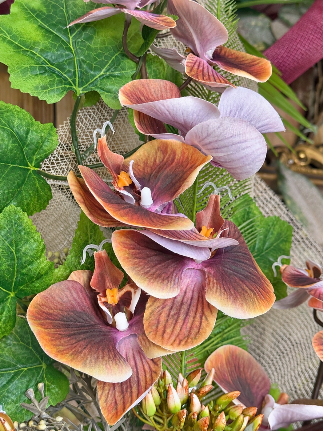 Dettaglio di orchidee artificiali nei toni malva e rame, in negozio da I fiori di Marina