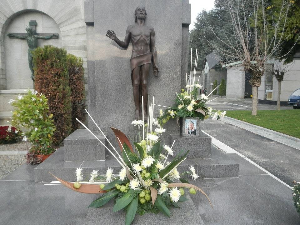 Composizioni floreali con crisantemi bianchi e foglie verdi su un monumento cimiteriale